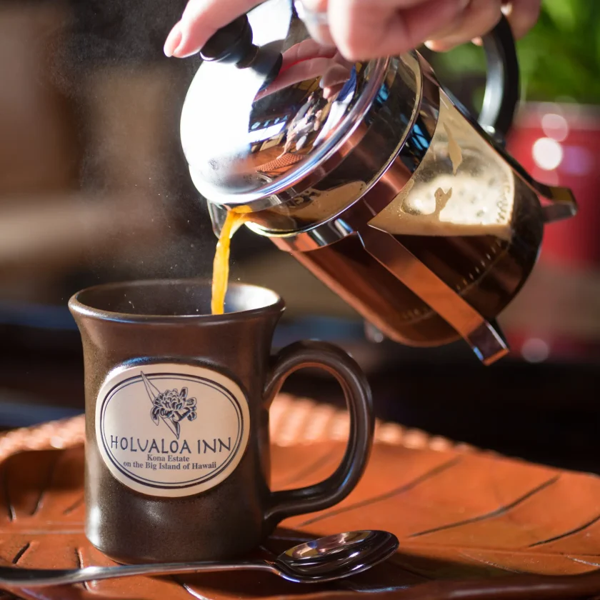 Pouring hot Kona coffee from French press into Holualoa Inn mug