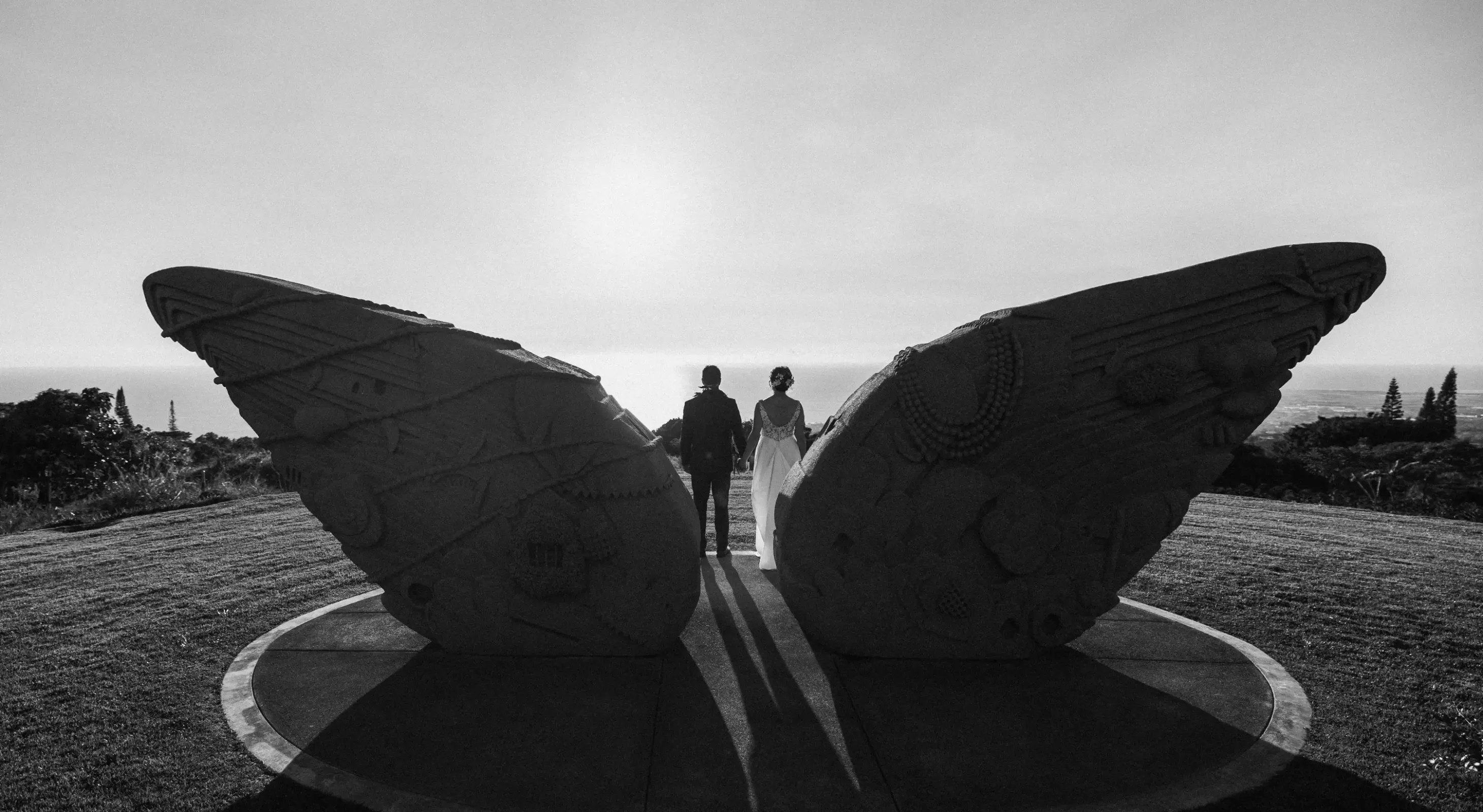 Wedding couple silhouetted at sculpture garden with panoramic ocean views on Hawaii’s Big Island