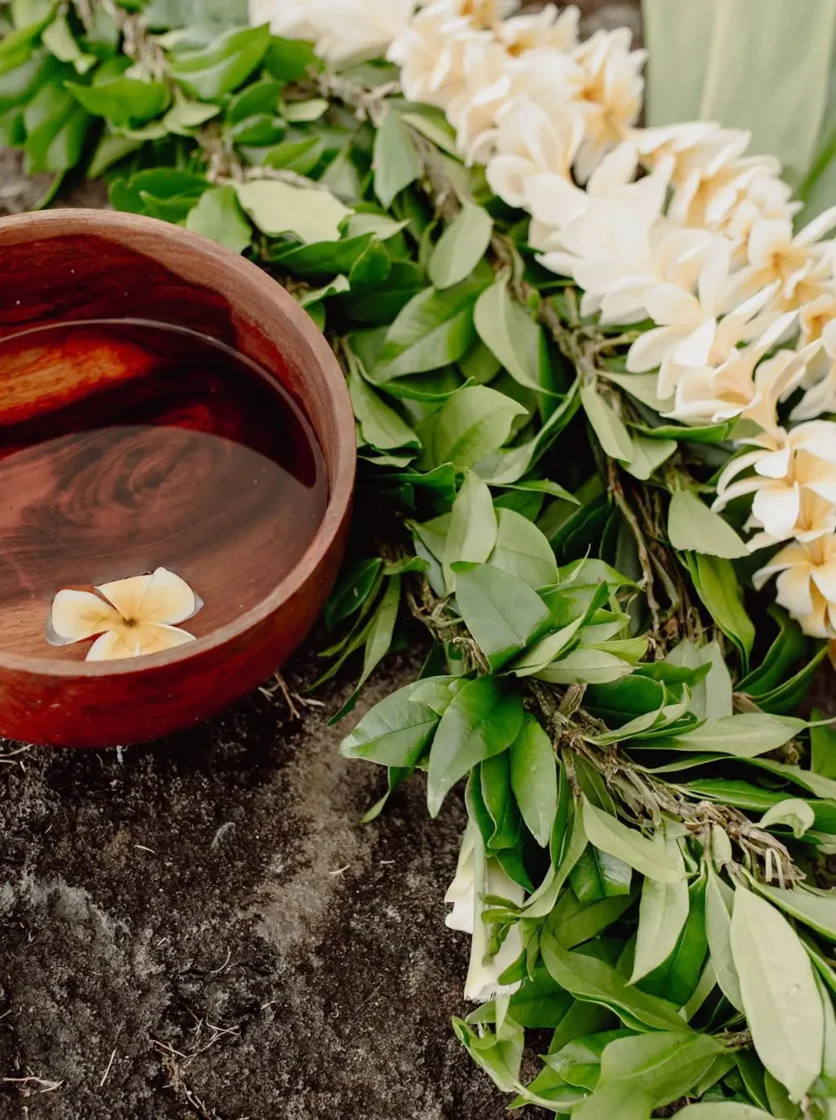 Leis and wooden bowl on lava rock - Traditional Hawaii Wedding Traditions