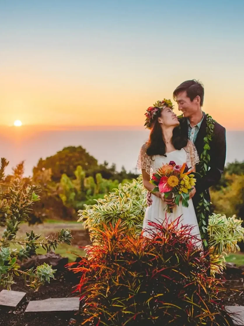 Couple with ocean views and a sunset after their Big Island wedding