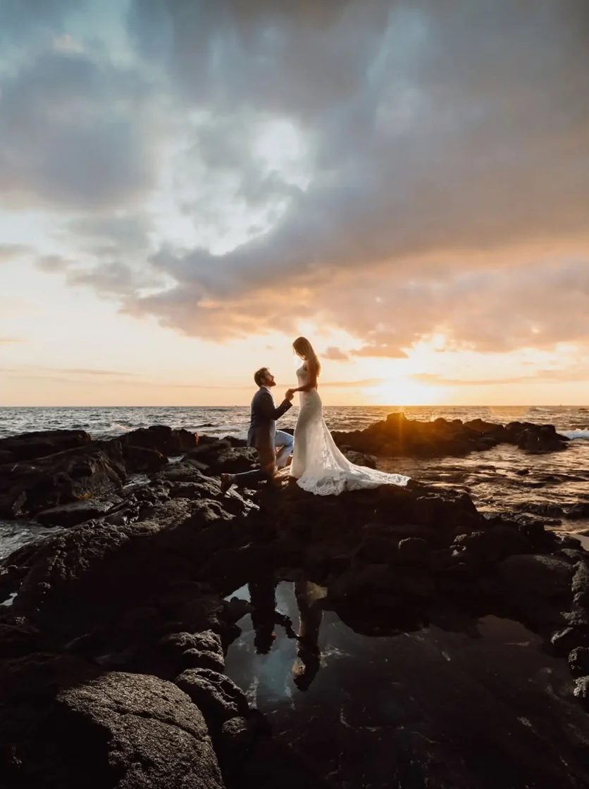 Wedding couple walking on black lava rocks at sunset
