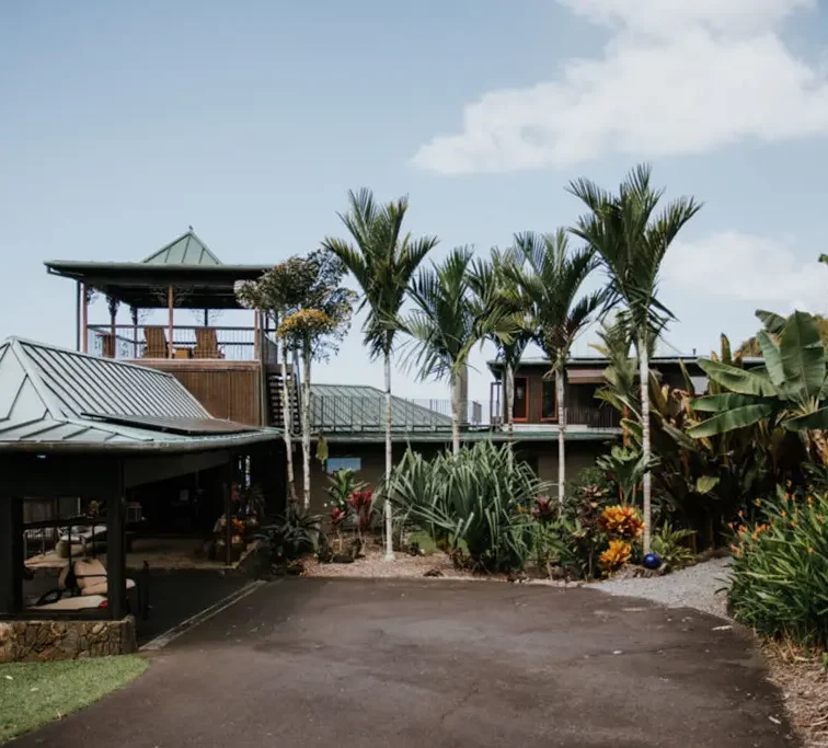 Driveway entrance to Holualoa Inn with rooftop gazebo and lush tropical landscaping in Hawaii