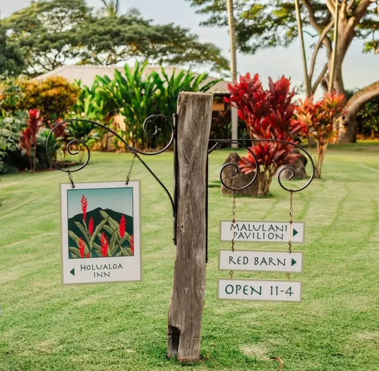 Directional signs on Holualoa Inn property for the Main Inn, Malulani Pavilion, and Red Barn surrounded by tropical gardens on the Big Island